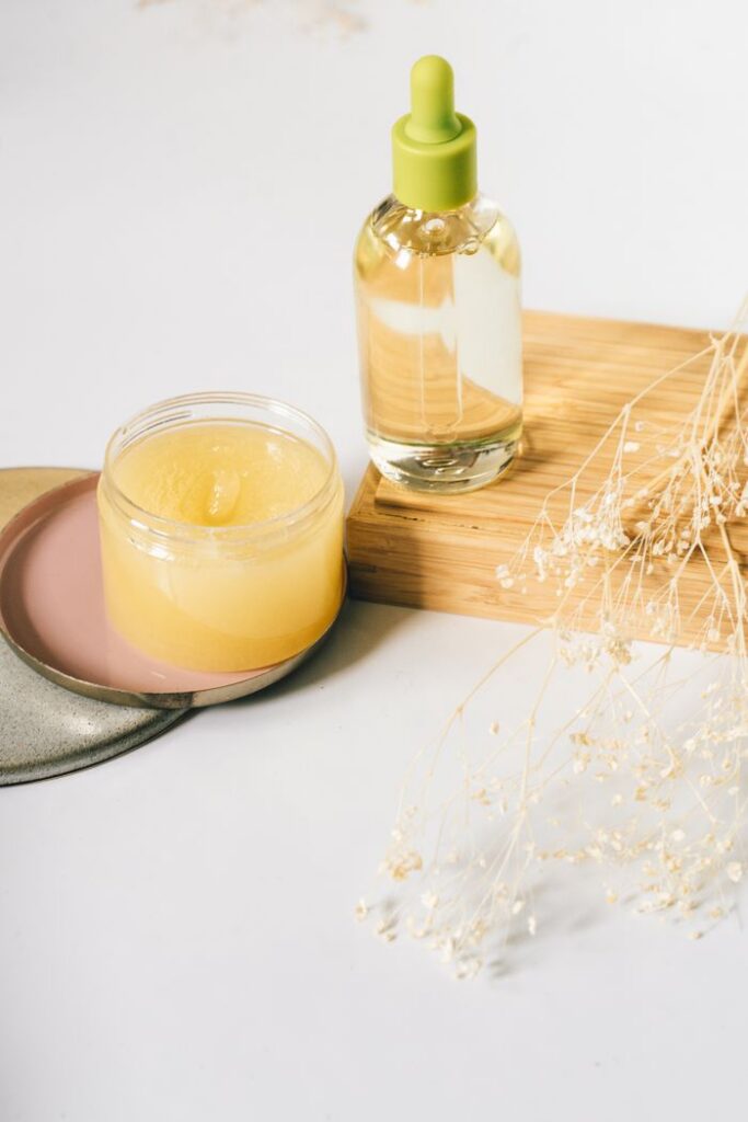 Aesthetic display of skincare oil and balm with dried flowers on a wooden surface.